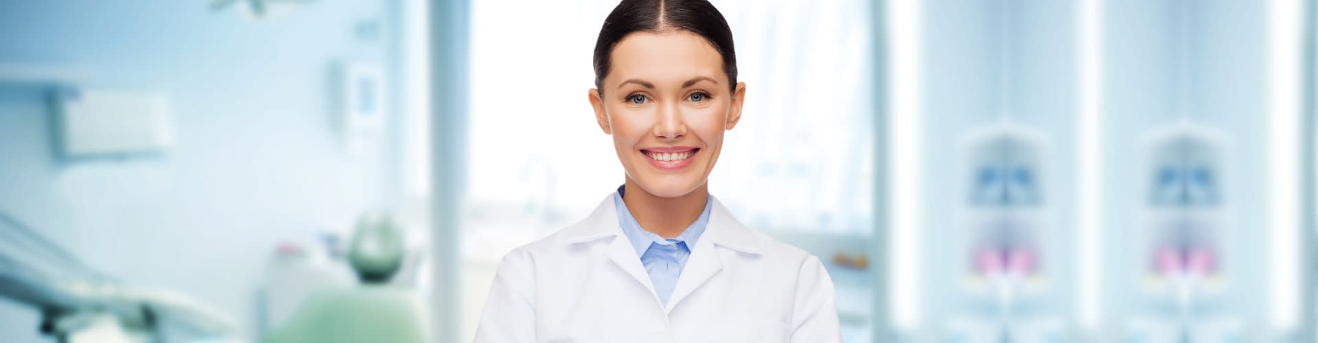 happy young female dentist with tools over medical office background