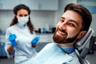 beautiful women dentist in the mask examines a patient in the dental office
